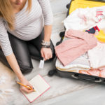 Pregnant woman packing for hospital and taking notes